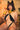 Momokun wearing a black strappy outfit, cat ears and gold jewelry against a brick wall