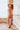 Woman in colorful lingerie standing in a softly lit room.