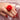 Hand wearing a red rose-shaped ring vibrator on a pink satin background with 'BLOOMGASM' branding.