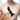 Black silicone butt plug held by a hand with a blurred background