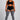 A woman modeling a black sports bra and matching black athletic shorts with white side stripes, paired with gray ribbed thigh-high socks, against a light gray studio background.