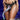 Person wearing a black harness with a colorful tentacle dildo, branded 'Creature Cocks', on a dark background.