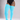 A model wearing bright turquoise ribbed thigh-high socks or stockings with a black bodysuit, standing against a neutral gray studio background.