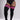 Black ribbed over-the-knee socks with three bright pink stripes at the top, shown on a model wearing a black bodysuit against a light gray studio background.