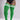 A model wearing bright green ribbed thigh-high socks with white stripes near the top, paired with a black bodysuit against a light gray studio background.