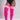 A model wearing bright pink ribbed over-the-knee socks with three white stripes near the top, paired with a black bodysuit, shown against a light gray studio background.