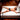 Man lying on a bed with straps around his wrists and ankles in a room with wooden flooring.