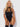 Model wearing a black strappy bodysuit against a white background