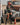 Woman in firefighter costume holding fire extinguisher in front of an old rusted truck in a desert setting.