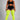 A model wearing a black sports bra and shorts with white side stripes, paired with bright neon yellow thigh-high socks, against a solid gray studio background.