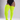 A model wearing bright neon yellow-green ribbed thigh-high socks or over-the-knee socks, paired with a black bodysuit, shown from the waist down against a light gray studio background.