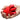 A hand holding a red Bloomgasm Petal Kiss Kissing and Licking Vibrator against a plain white background, with small white arrow and wavy line graphics indicating texture or function.