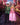 Woman wearing a pink Popular Witch adult halloween costume standing next to a man wearing a green and black costume