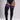 Black ribbed over-the-knee socks with three purple stripes near the top, worn by a model in a black bodysuit against a light gray studio background.