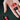 Hand holding two dice, one red and one black with Spanish text, on a dark background