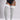 A model wearing light gray ribbed over-the-knee socks with white stripes near the top, paired with a black bodysuit. The photo is cropped from the chest down against a neutral gray studio background.