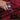 Hand pouring water from a clear glass container onto a red blanket