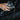 Hand with a ring holding a glass over water on a dark background