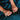 Close-up of hands holding a knife against a dark blue fabric background