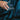 Hand pouring water from a clear glass container into another container against a dark background