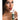 Woman holding a green spray bottle labeled 'SUCK IT' against a white background
