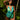 Woman wearing a green and blue tropical print romper standing in a tropical setting with palm leaves.