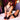 Woman wearing a black harness sitting on a bed in a dimly lit room.