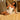 Woman in a white lace nightgown sitting on a gold bedspread.